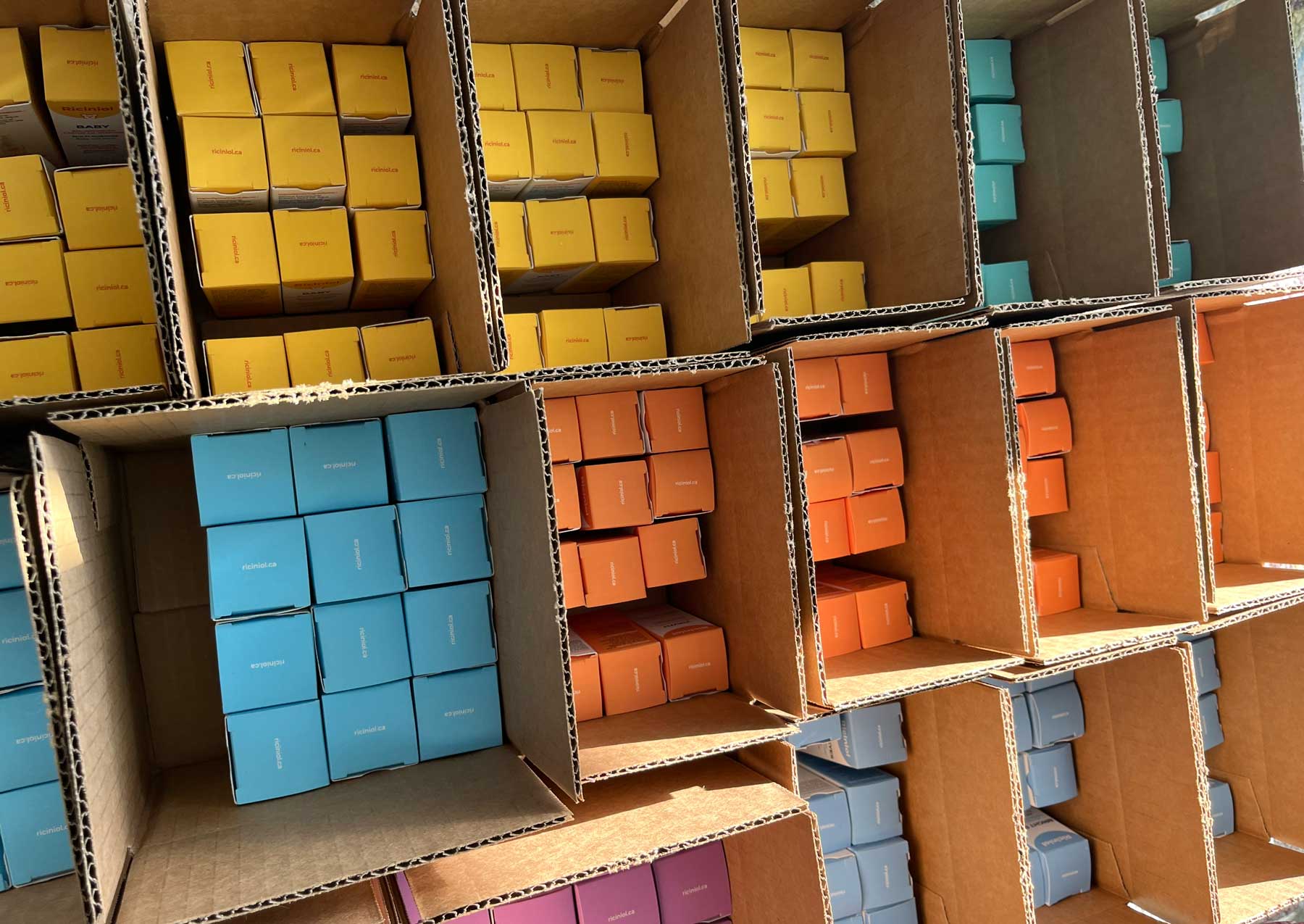 Stacks of colorful Riciniol product boxes ready to ship